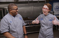 Chef Ted and Chef Jessie in the kitchen. Chef Jessie smiling and giving two thumbs up.