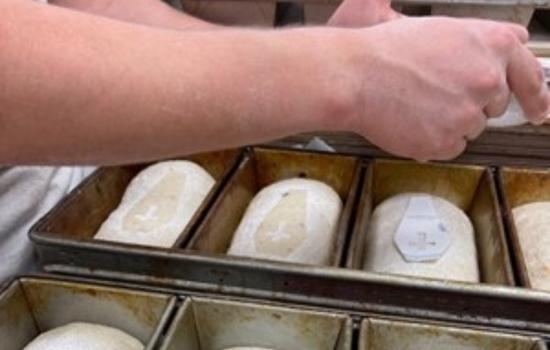 Rockin’ Baker cadet employee sprinkles flour on top of the Vampire’s Worst Enemy loaf.