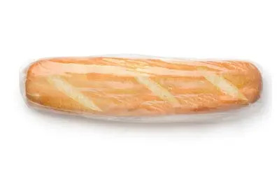A baguette encased in plastic, set on a white surface.