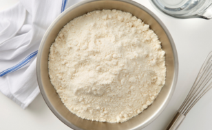 Mixing bowl filled with flour with dishtowel in background